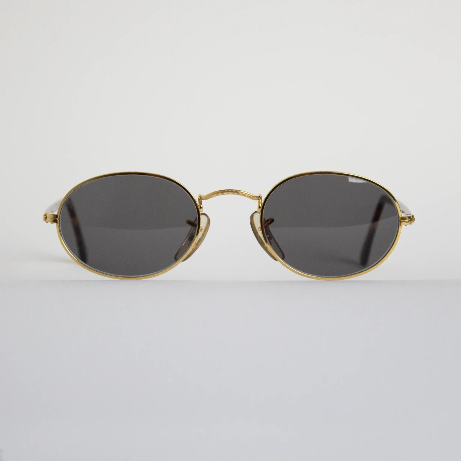 Vista frontal: Gafas vintage Ray-Ban Gold, diseño ovalado en dorado con cristales verdes.